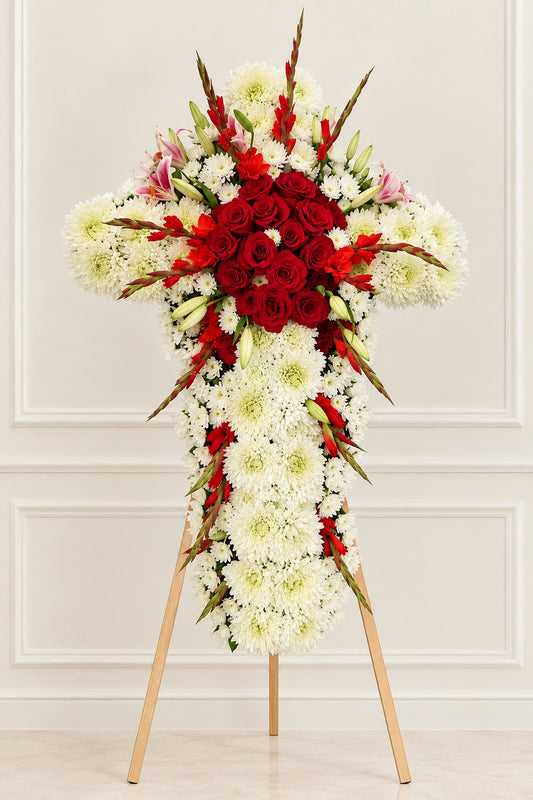 White chrysanthemum funeral cross with red roses, red gladiolus, and pink stargazer lilies on a standing easel